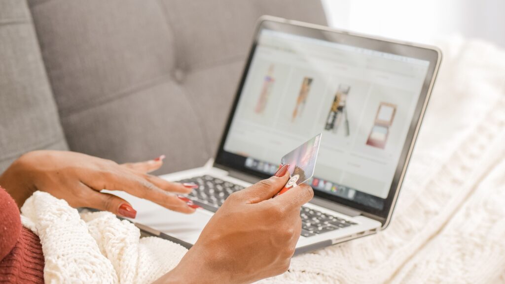 pexels-photo-7007174-7007174 A woman relaxes on a couch while shopping online using her laptop and credit card.